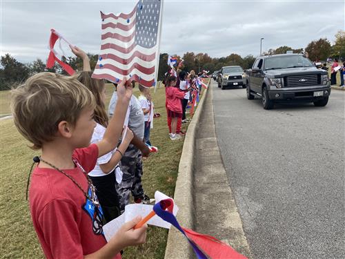 Students lining parade route with flags 